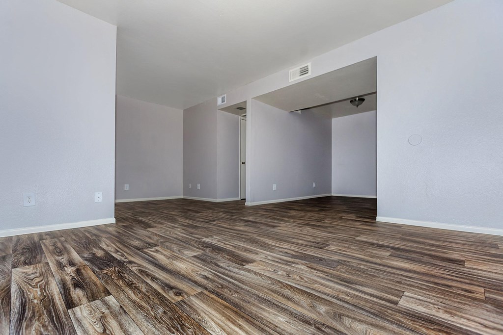 the living room and dining room of an apartment with wood flooring