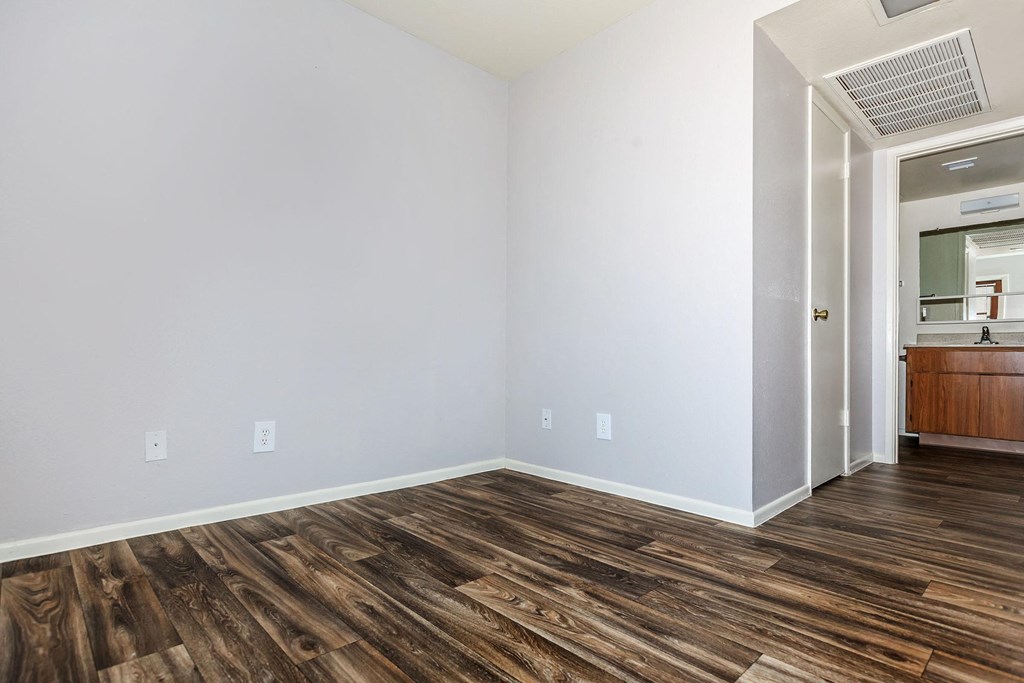 a room with white walls and wood flooring and a bathroom