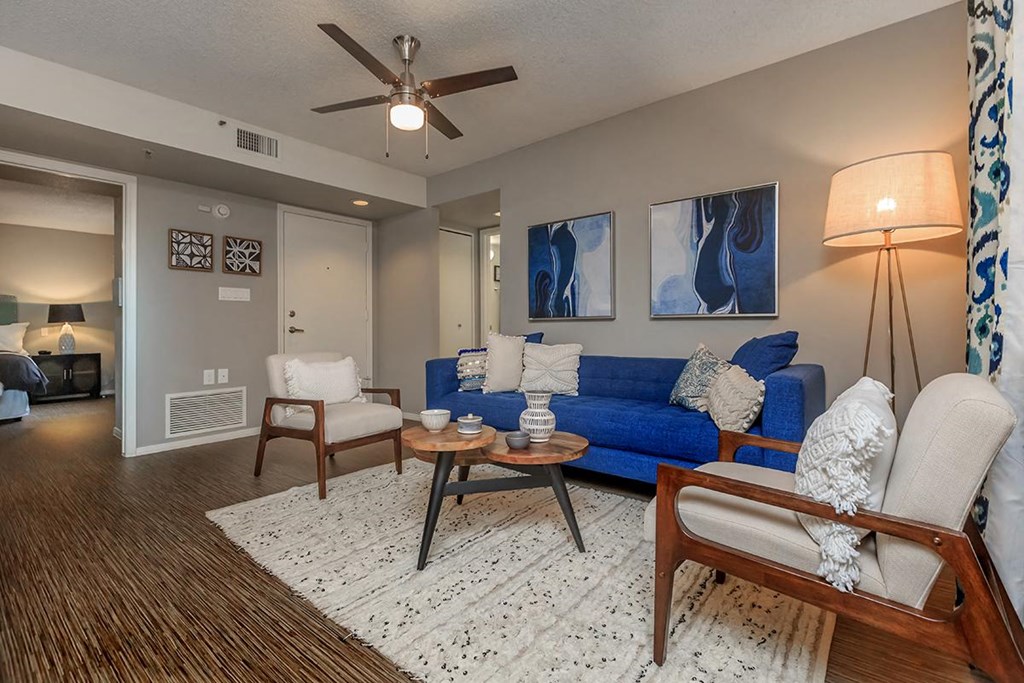 a living room with a blue couch and a ceiling fan