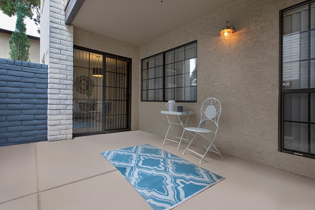 a patio with a blue rug and two chairs on it