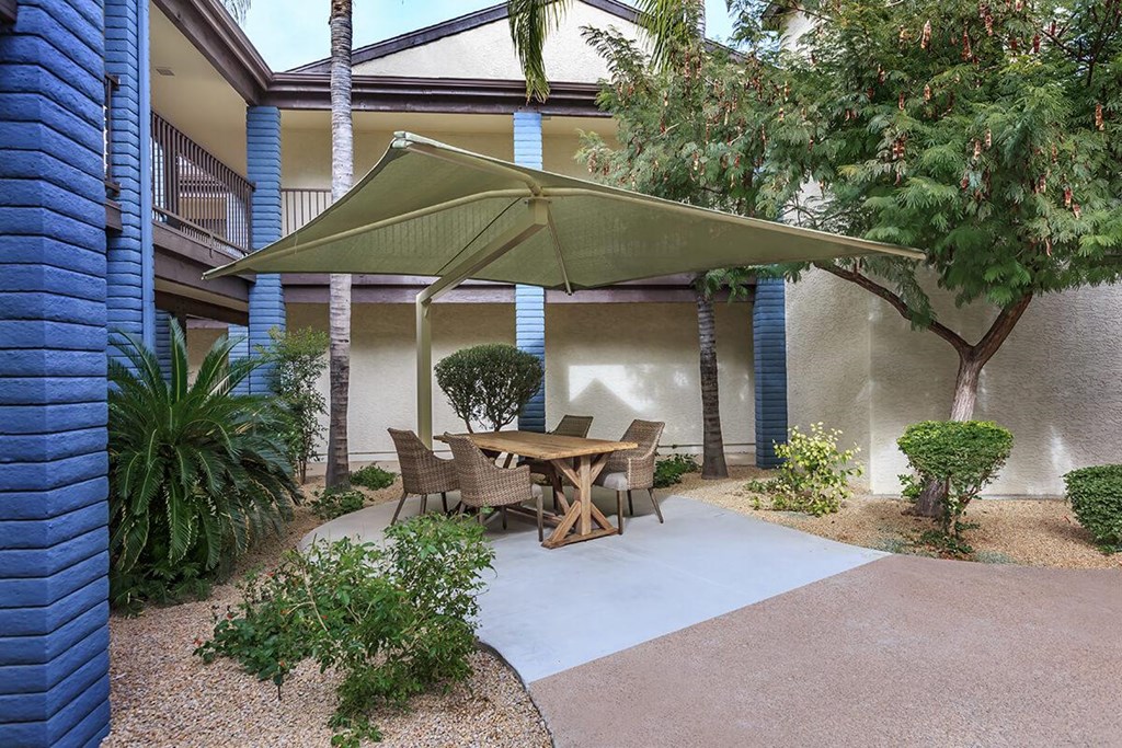 a patio with a table and chairs under an umbrella