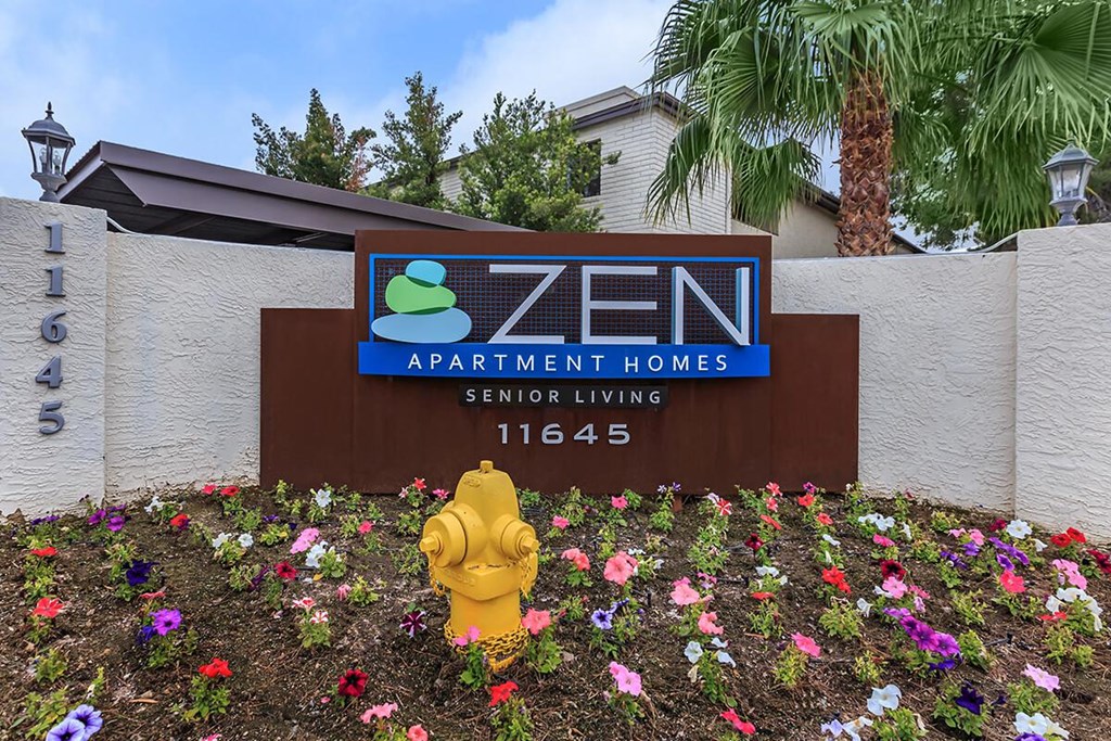 a yellow fire hydrant in front of a zen apartment homes sign
