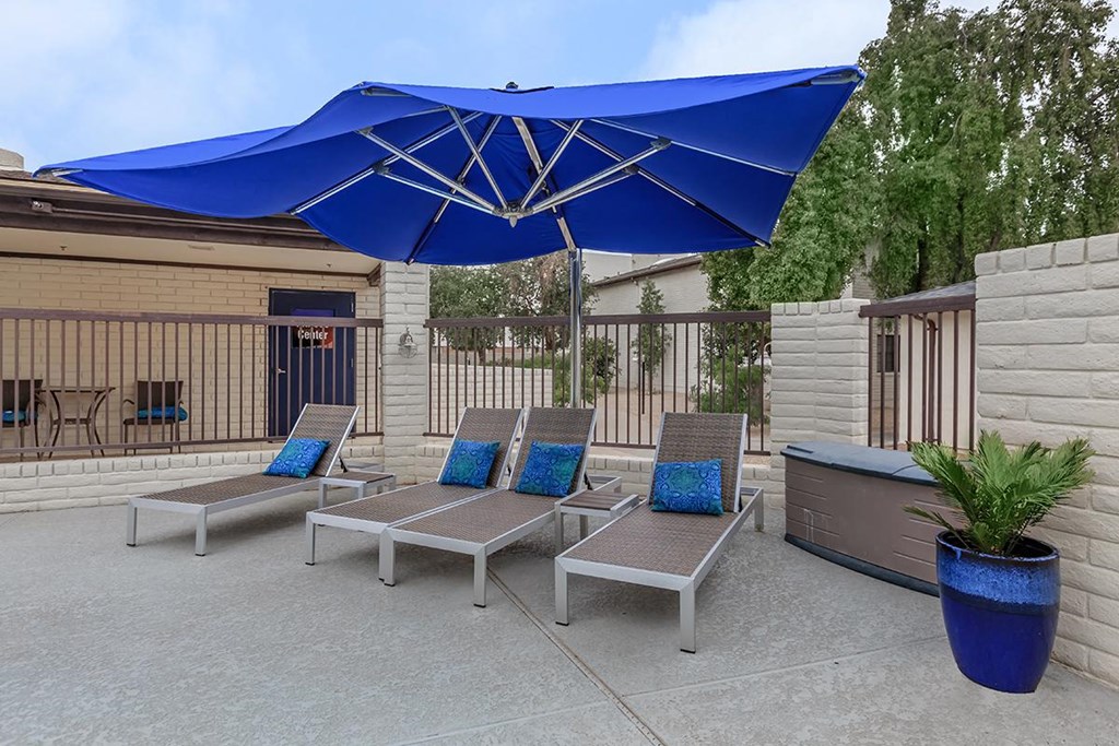 a patio with lounge chairs and an umbrella