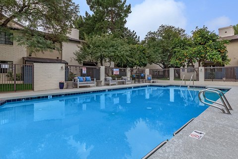 a large blue pool in front of a building with trees