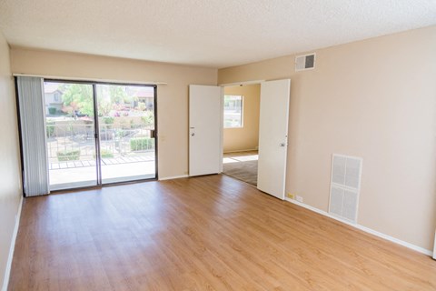 an empty living room with wood floors and a sliding glass door
