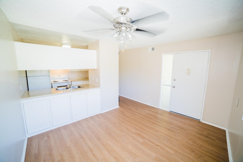an empty living room with white cabinets and a ceiling fan