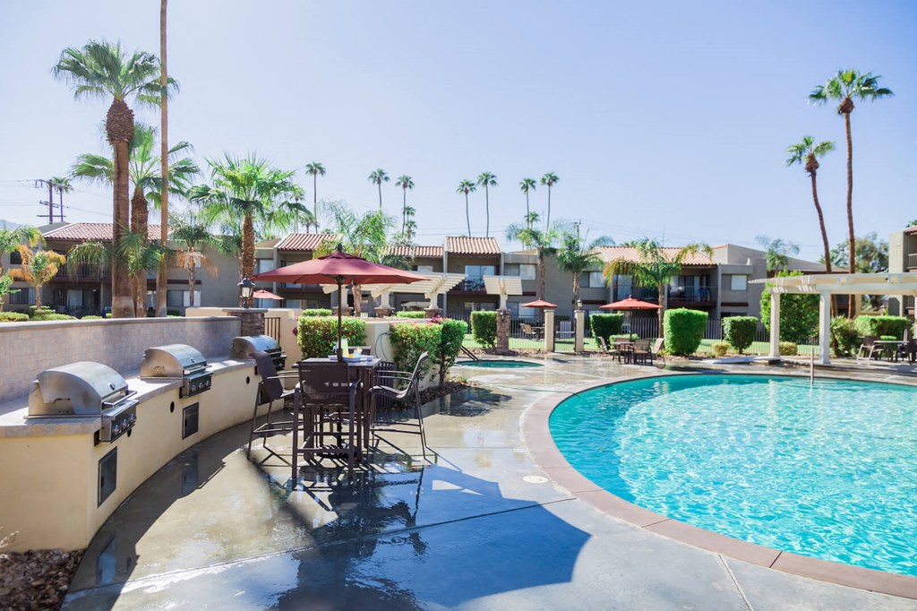 a resort style pool with tables and umbrellas at the resort