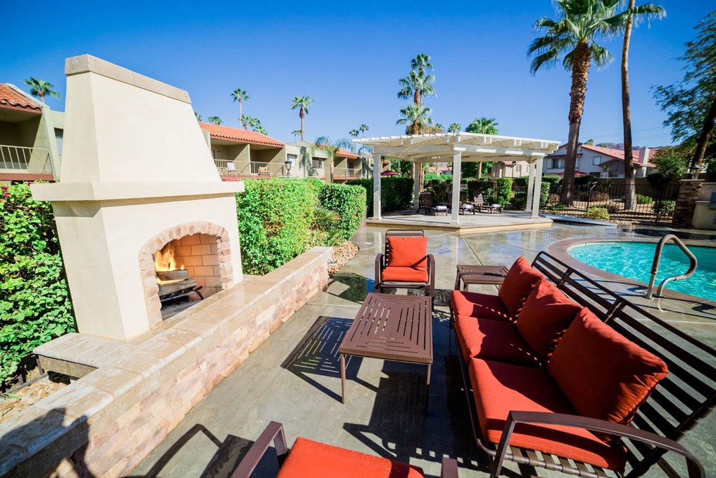 a patio with furniture and a fireplace next to a pool