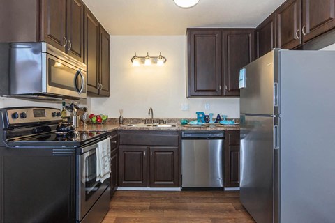A kitchen with dark wood cabinets and stainless steel appliances.