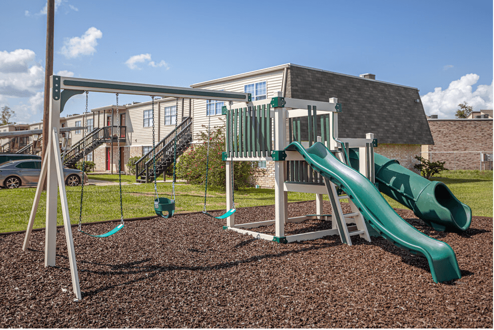 a playground with a slide and swings in front of a house