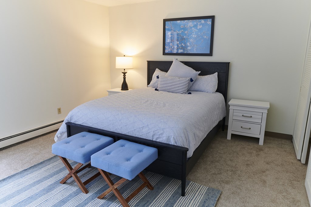 a bedroom with a bed and two stools