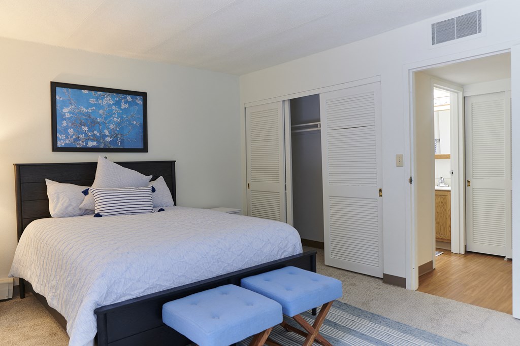 a bedroom with a bed and two blue stools
