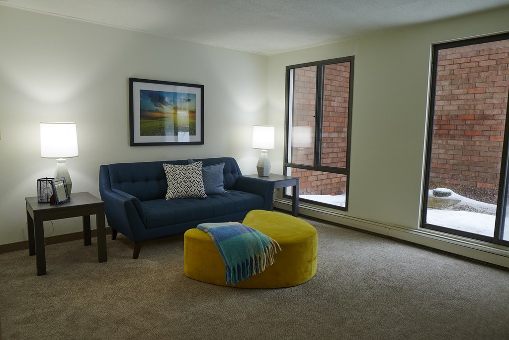 a living room with a blue couch and a yellow ottoman