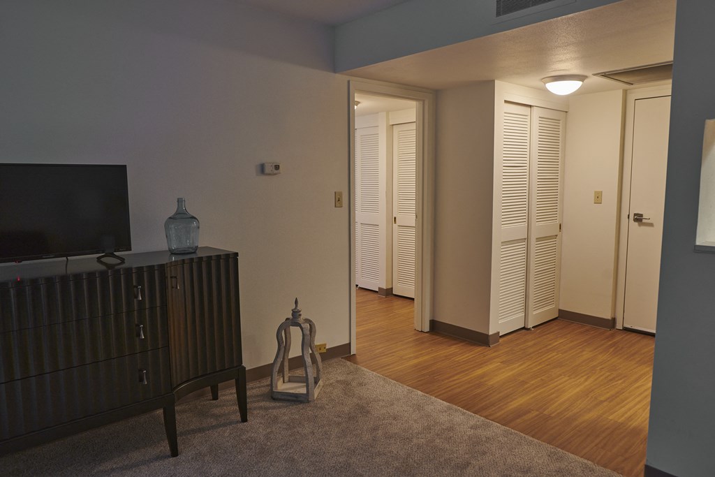 a living room with a dresser and a tv and a door to a hallway