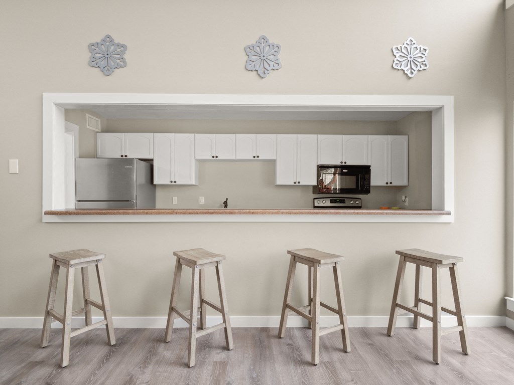 a bar with three stools in a room with a kitchen
