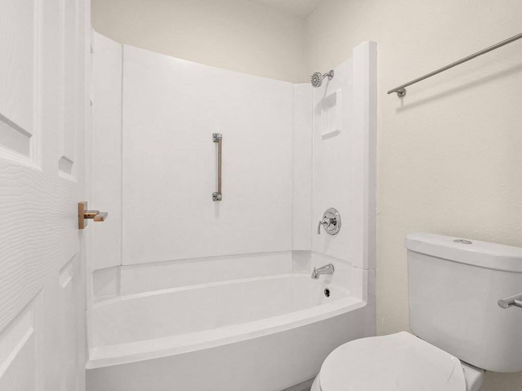 a white bathroom with a white toilet and a white tub