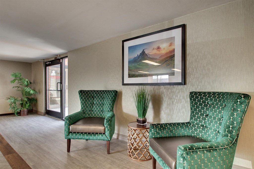 a living room with two green chairs and a painting on the wall