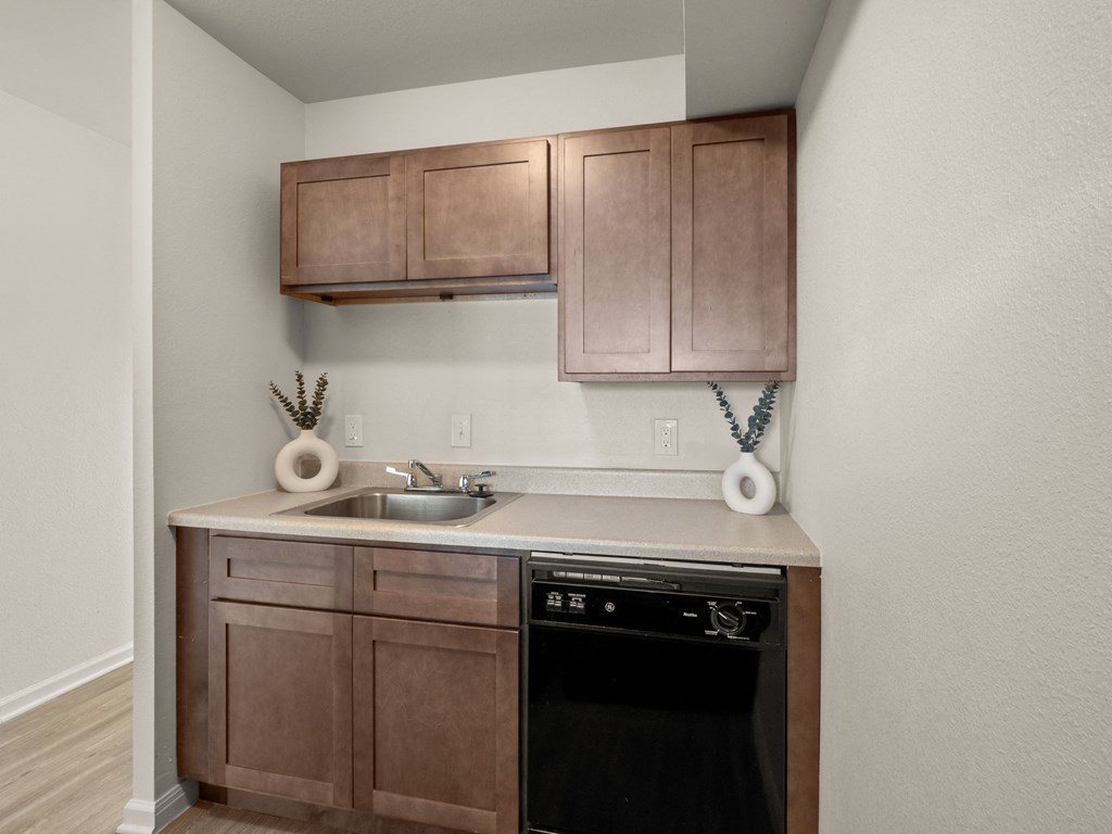 an empty kitchen with wooden cabinets and a black dishwasher