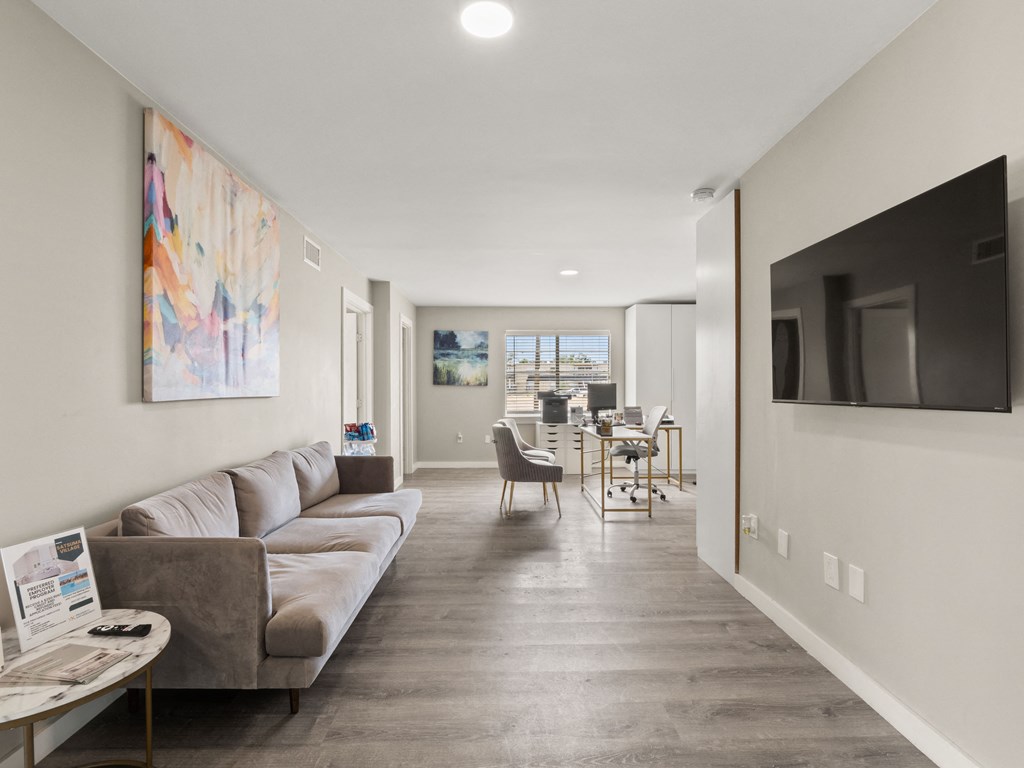 the living room and dining room of an apartment with a couch and a tv