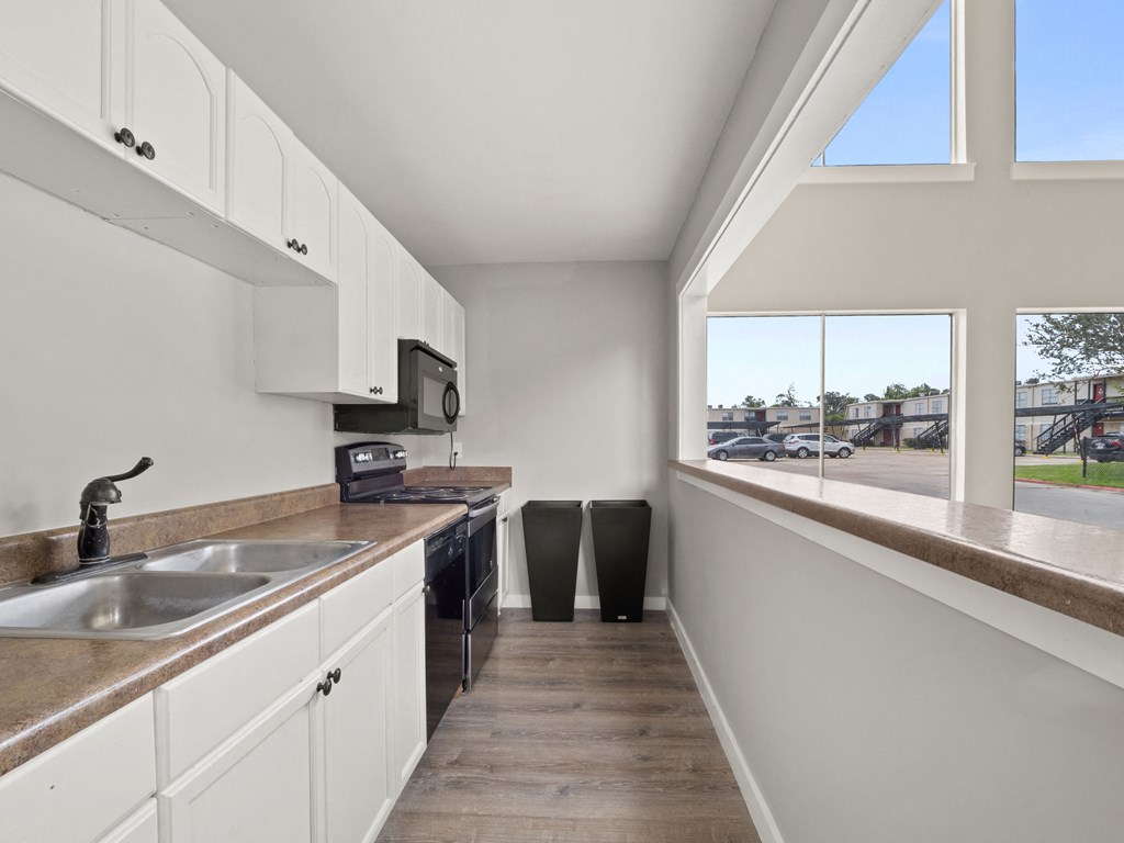 a kitchen with white cabinets and a sink and a window