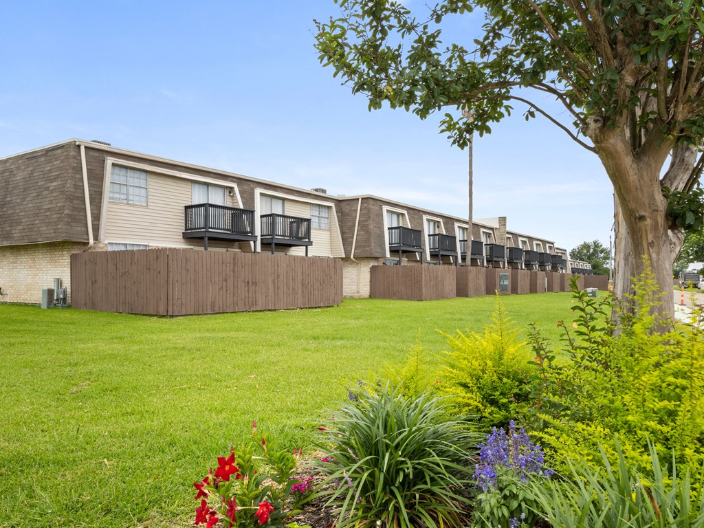 a row of apartments with balconies and grass and flowers