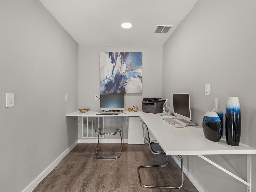 a home office with a white desk and a painting on the wall