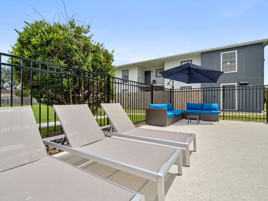 a patio with chairs and a table with an umbrella and a house