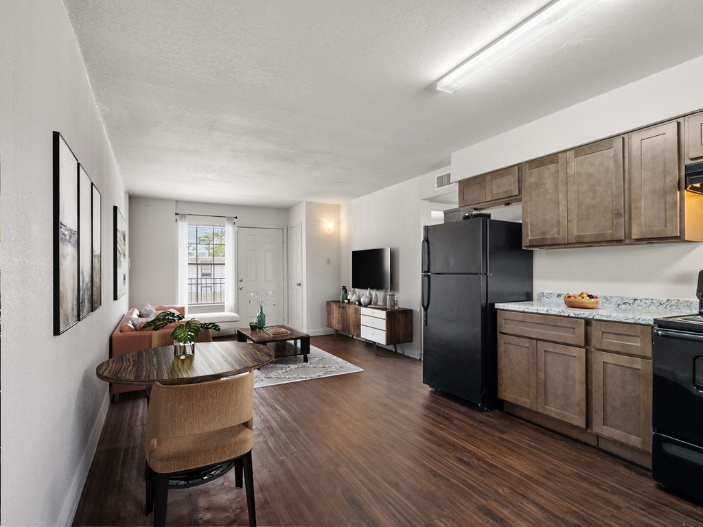 a kitchen and living room with a black refrigerator and a table