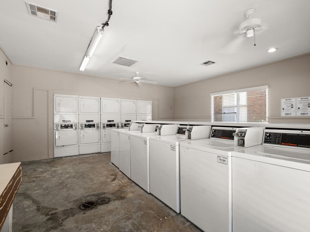 a laundry room with washers and dryers and a row of washer machines