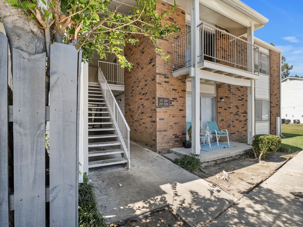 a small brick apartment building with stairs and a sidewalk