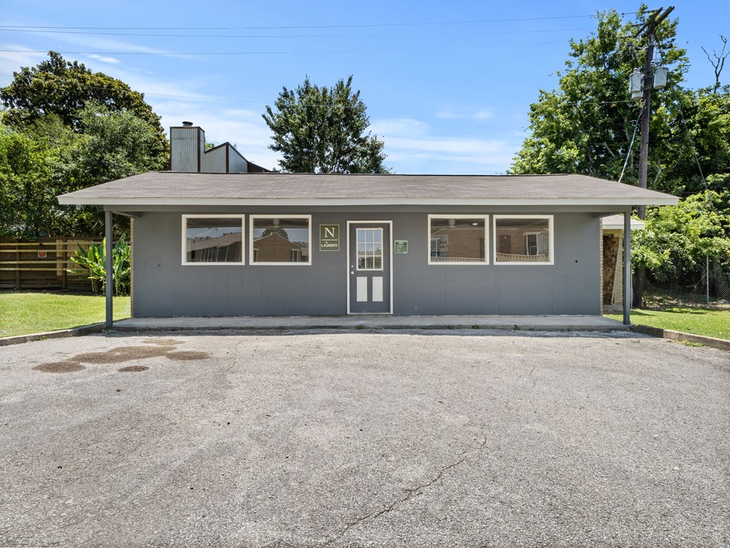 the front of a gray building with a parking lot