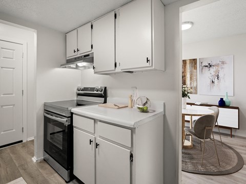 an open kitchen with white cabinets and a white counter top with a stove and oven