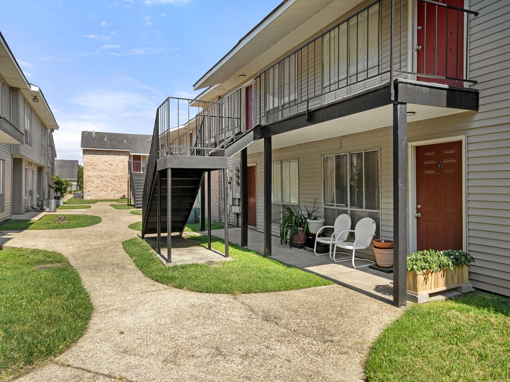 the yard of a house with a balcony and a staircase