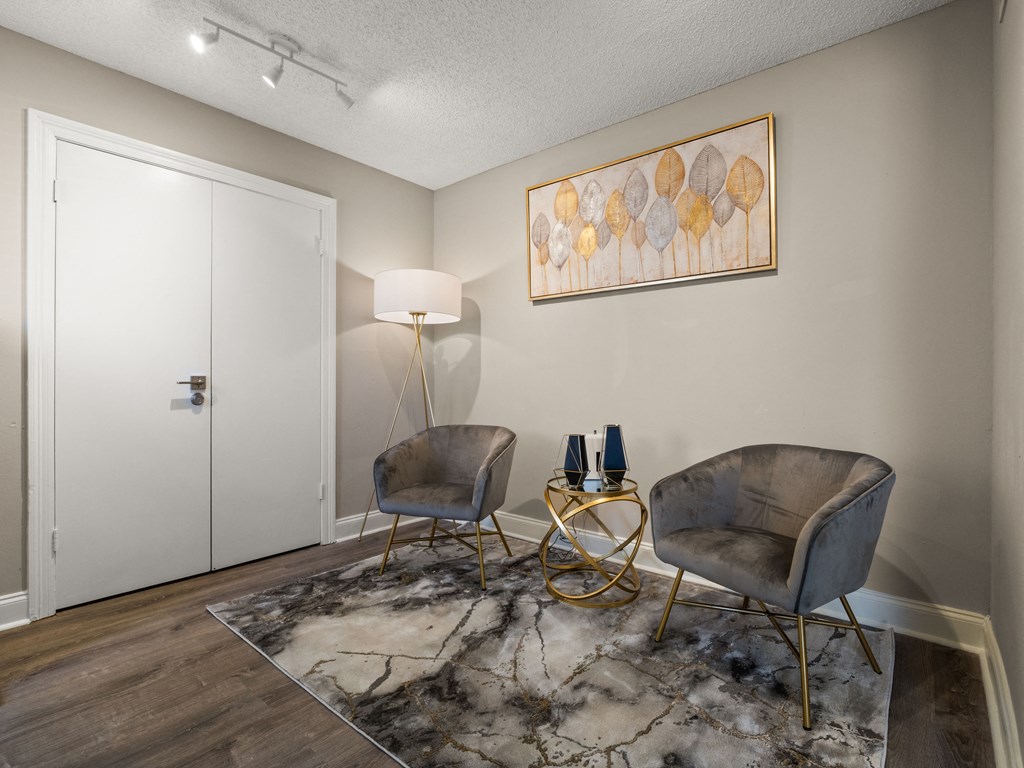 a living room with two chairs and a table and a lamp