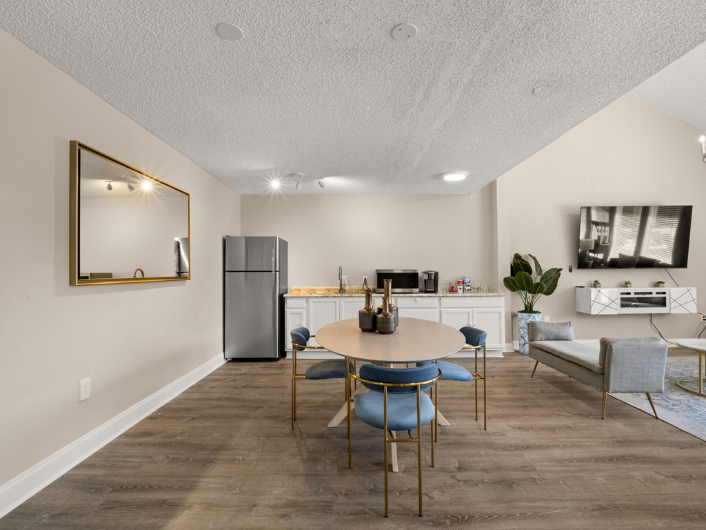 a dining room with a table and chairs and a kitchen with a refrigerator
