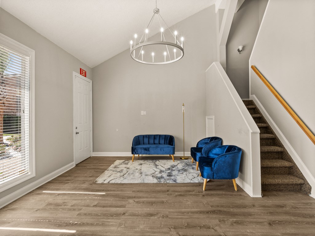 a living room with two blue chairs and a staircase