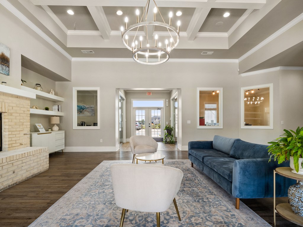 a living room with a blue couch and white chairs and a chandelier