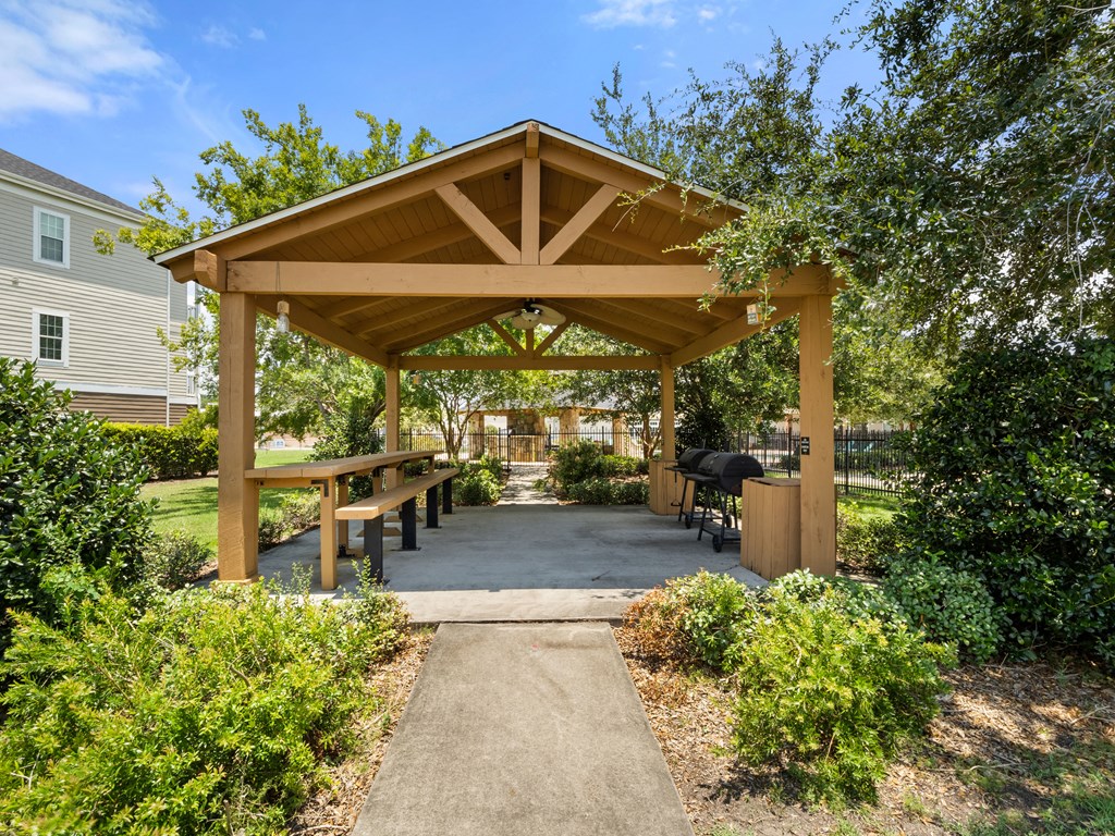 a pavilion with benches and a picnic table in a park
