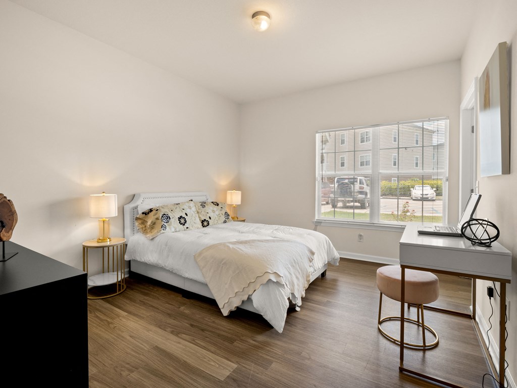 a bedroom with a bed and a desk and a window