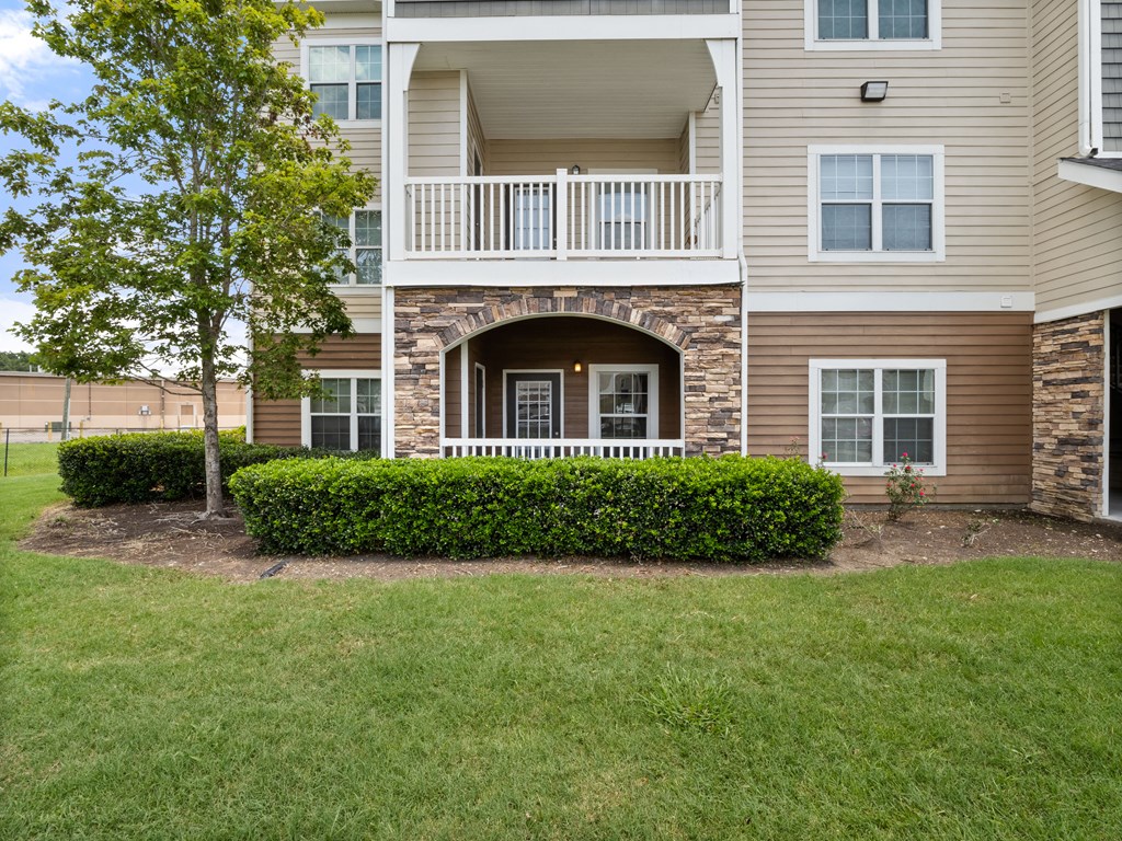 front view of an apartment building with a porch and landscaping