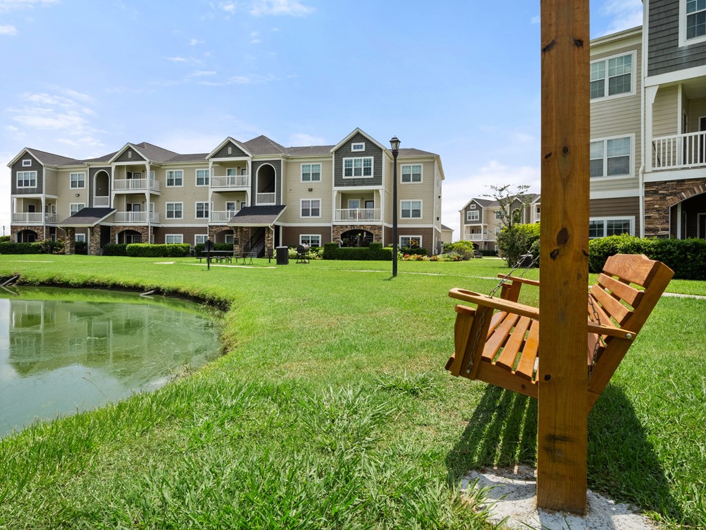 a park bench overlooking a pond in front of an apartment building