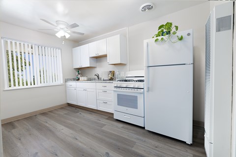 A white refrigerator stands in a kitchen with a fan on the ceiling.