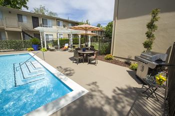 Pool area patio with a grill and a table and chairs at Abby Creek Apartments, California 