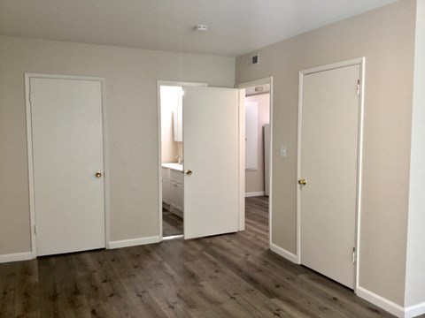 an empty living room with white doors and a wood floor