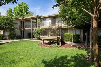 Apartment building with a staircase, and sidewalk and trees in front of it at Abby Creek Apartments, California 