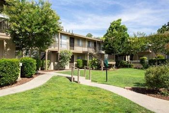 Apartment building with a green yard and sidewalk at Abby Creek Apartments, Carmichael 