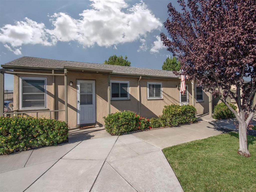 a tan house with a sidewalk and a tree in front of it