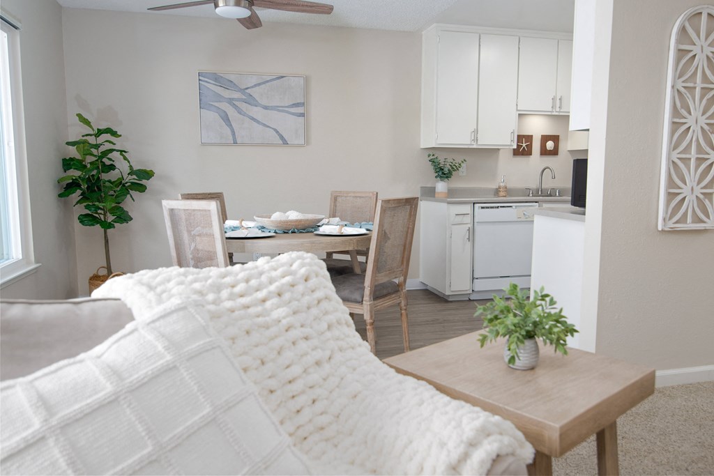 Model apartment living room with a couch and a table and a kitchen at Willow Grove Apartments, Sacramento California 