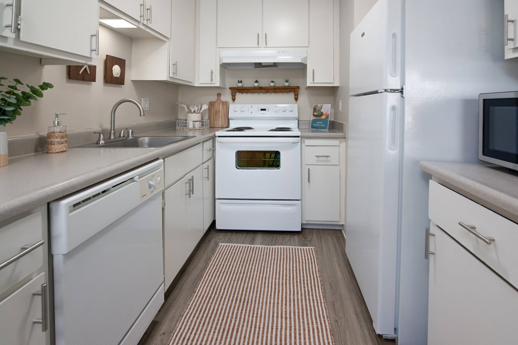 Model apartment kitchen with white appliances and white cabinets at Willow Grove Apartments, California, 95825