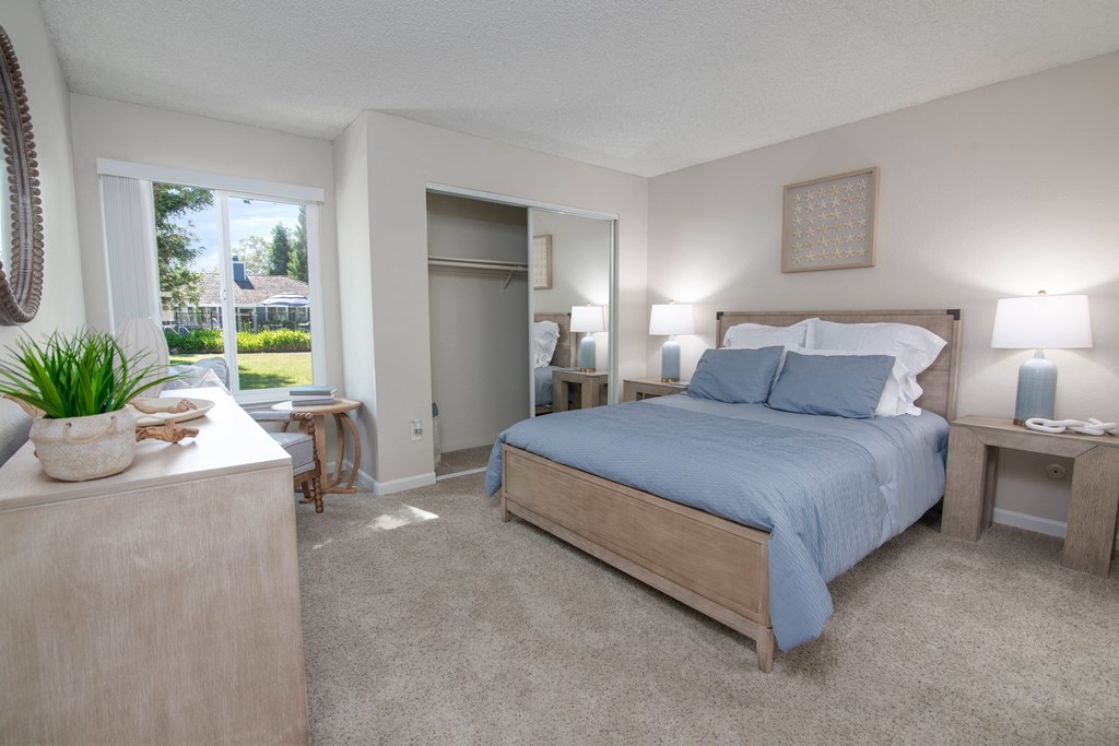 Model apartment master bedroom with a bed and a dresser and a window at Willow Grove Apartments, Sacramento, CA 95825